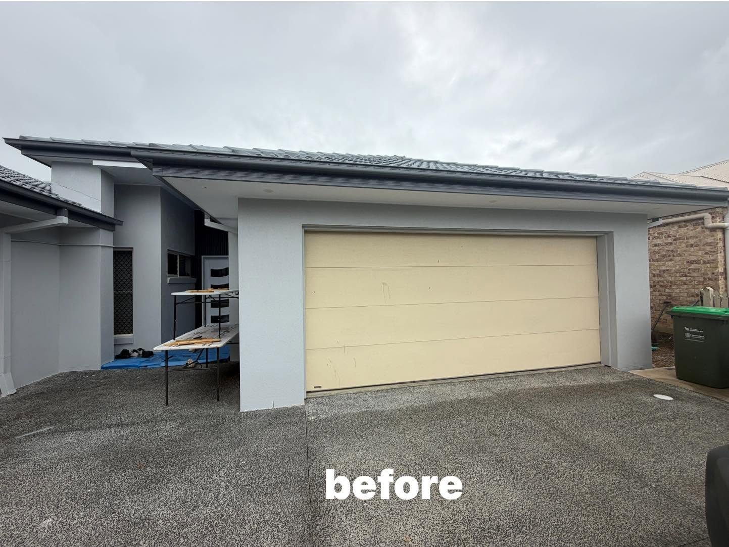 Before photo of a tired cream sectional garage door on a rendered Queensland home, ready to be replaced.
