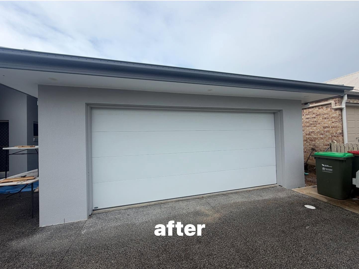 After photo of the same home with a new white flat-panel sectional garage door installed.