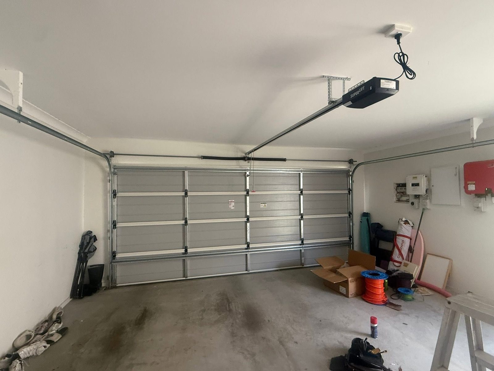 A finished sectional garage door seen from inside the garage, with the newly installed Superlift opener and rail mounted on the ceiling.